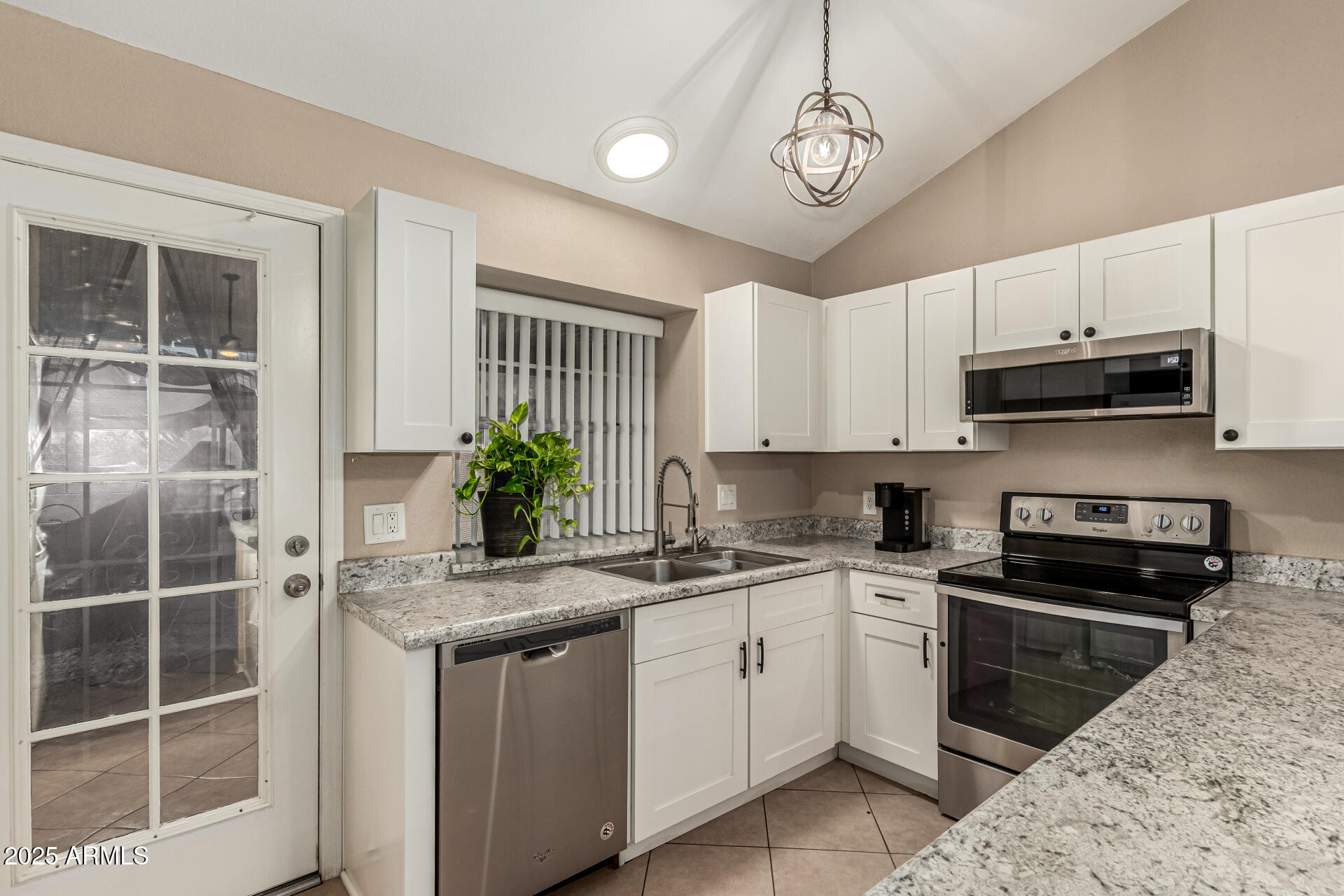 8111 West Wacker Road, Unit 1 Peoria, AZ 85381 - Photo 5 of 26 a kitchen with stainless steel appliances granite countertop a sink a stove a microwave and cabinets