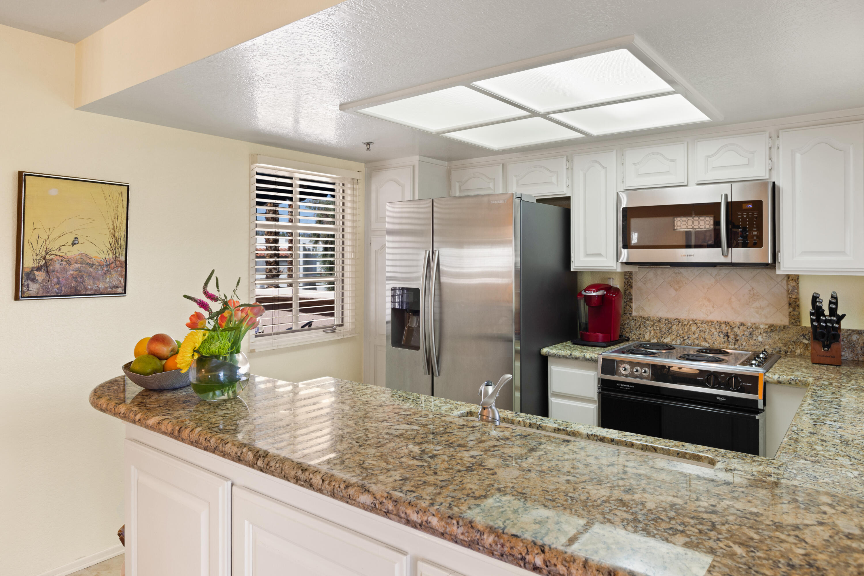 500 East Amado Road, Unit 613 Palm Springs, CA 92262 - Photo 13 of 28 a kitchen with stainless steel appliances granite countertop a sink a stove a microwave a refrigerator and island