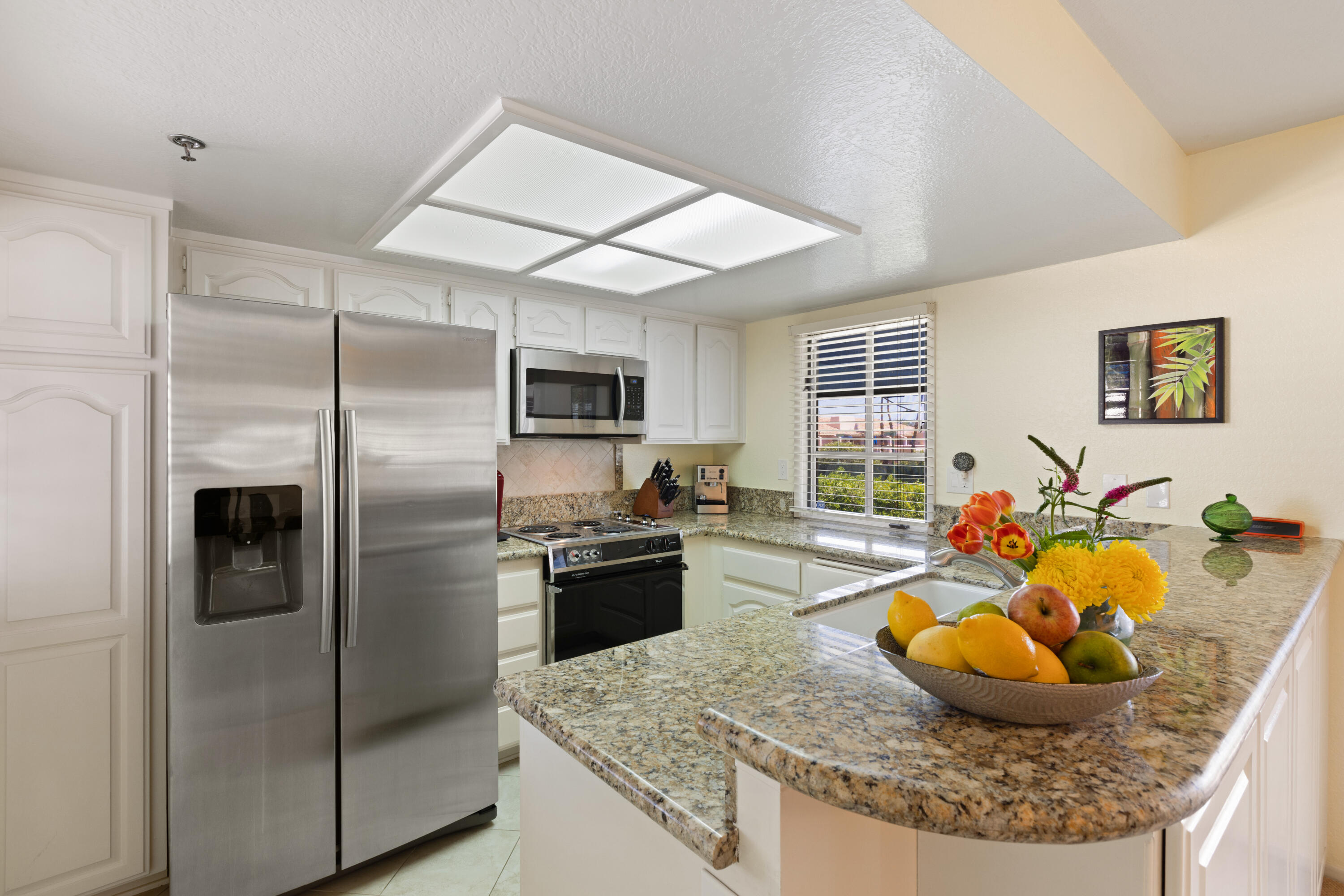 500 East Amado Road, Unit 613 Palm Springs, CA 92262 - Photo 14 of 28 a kitchen with stainless steel appliances granite countertop a sink refrigerator and microwave