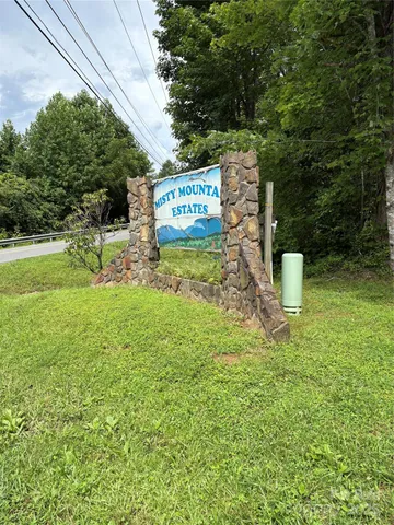 a sign board with a house in the background