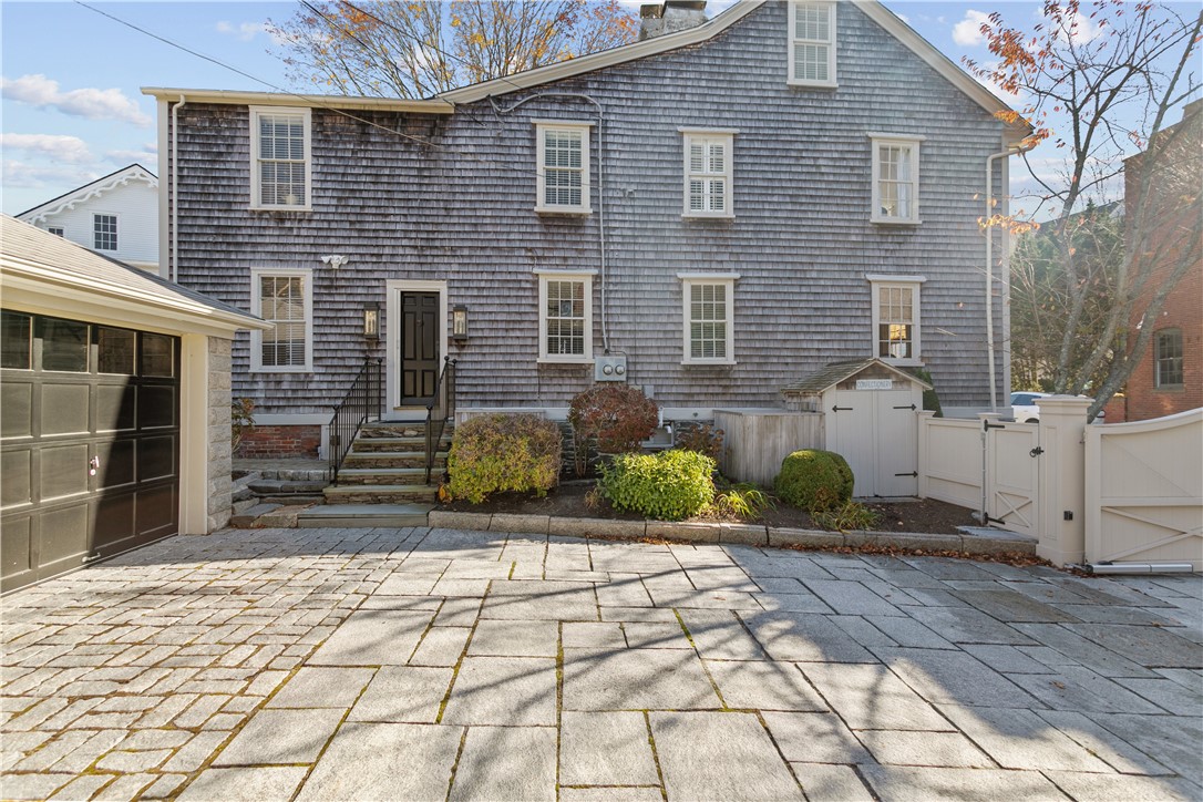 70 Mill Street Newport, RI 02840 - Photo 3 of 50 Granite courtyard/driveway leads to main residence side entrance door with features a low-profile "Phantom" pull-out Screen Door. Exterior details include wood clapboard and shingles.