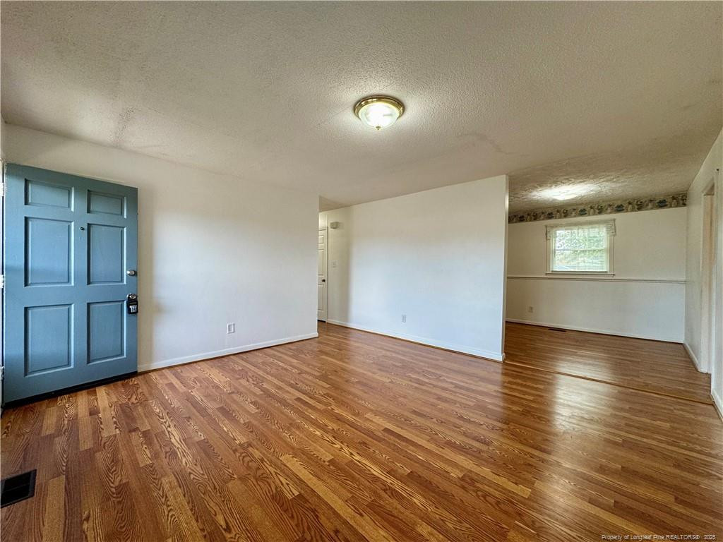 703 Odell Road Spring Lake, NC 28390 - Photo 3 of 21 an empty room with wooden floor and windows