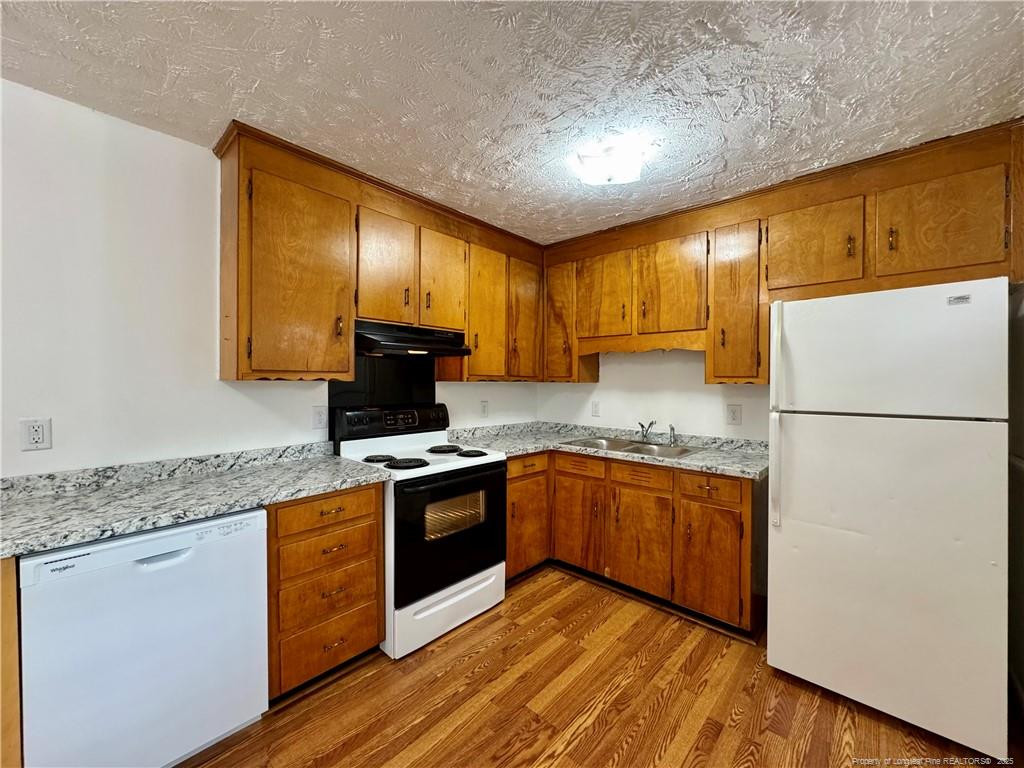 703 Odell Road Spring Lake, NC 28390 - Photo 7 of 21 a kitchen with granite countertop wooden cabinets a stove a sink and a refrigerator