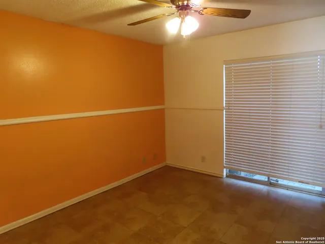 an empty room with a ceiling fan and a window