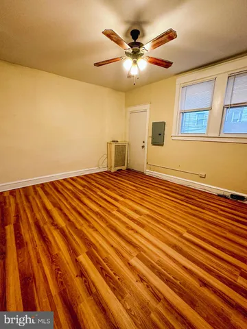 a view of an empty room with wooden floor and a chandelier