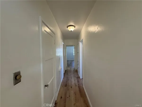 a view of a hallway with wooden floor and closet