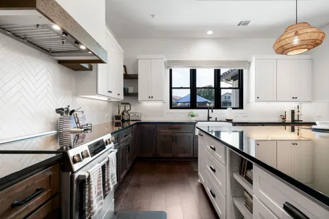 a kitchen with stainless steel appliances granite countertop a stove a sink a dining table and chairs with wooden floor