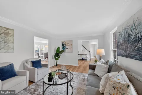 a living room with furniture couches and a dining table with wooden floor