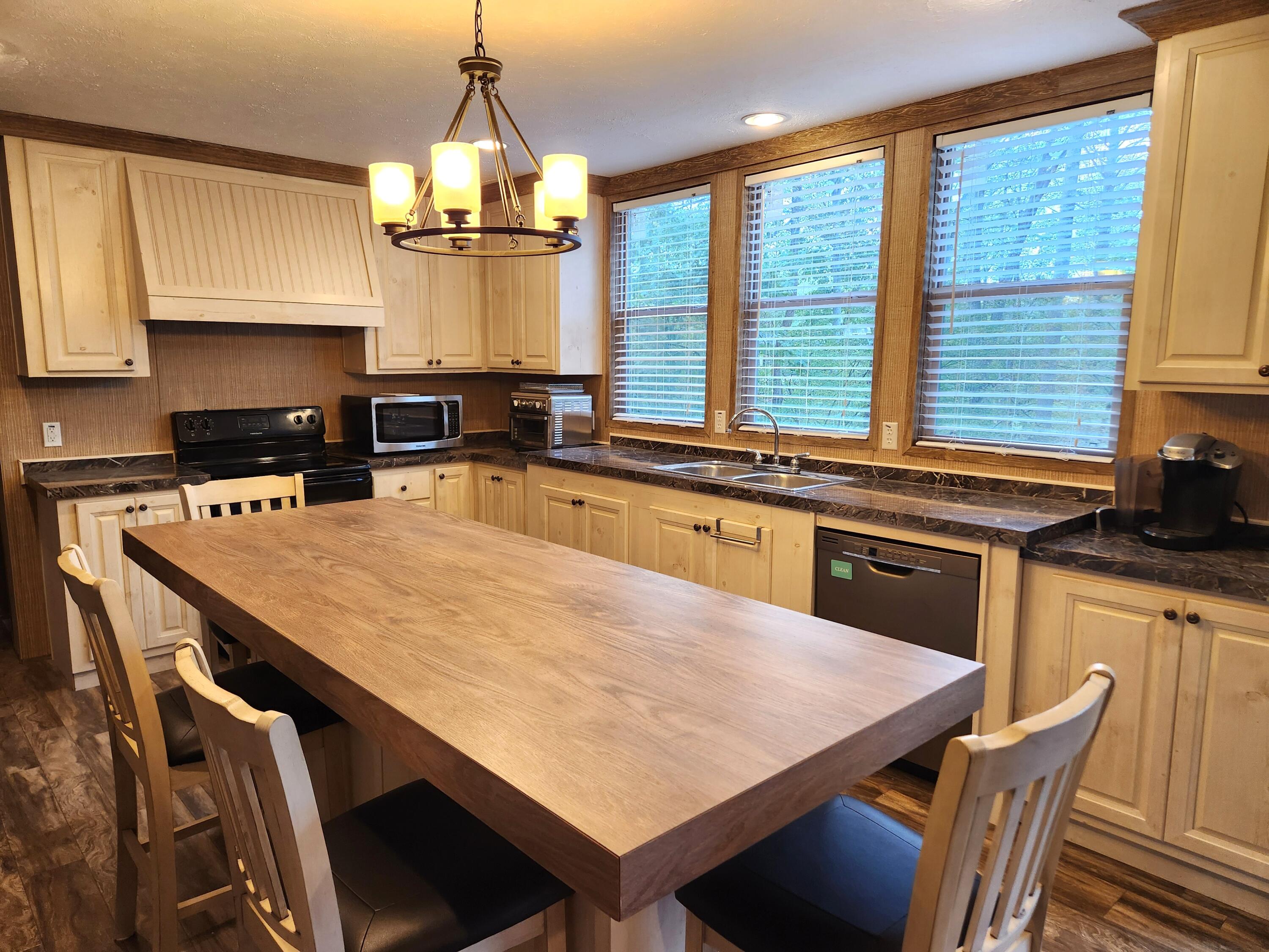 300 Whisperway Road Moneta, VA 24121 - Photo 6 of 24 a kitchen with a stove a kitchen island a sink dishwasher a dining table and chairs with wooden floor