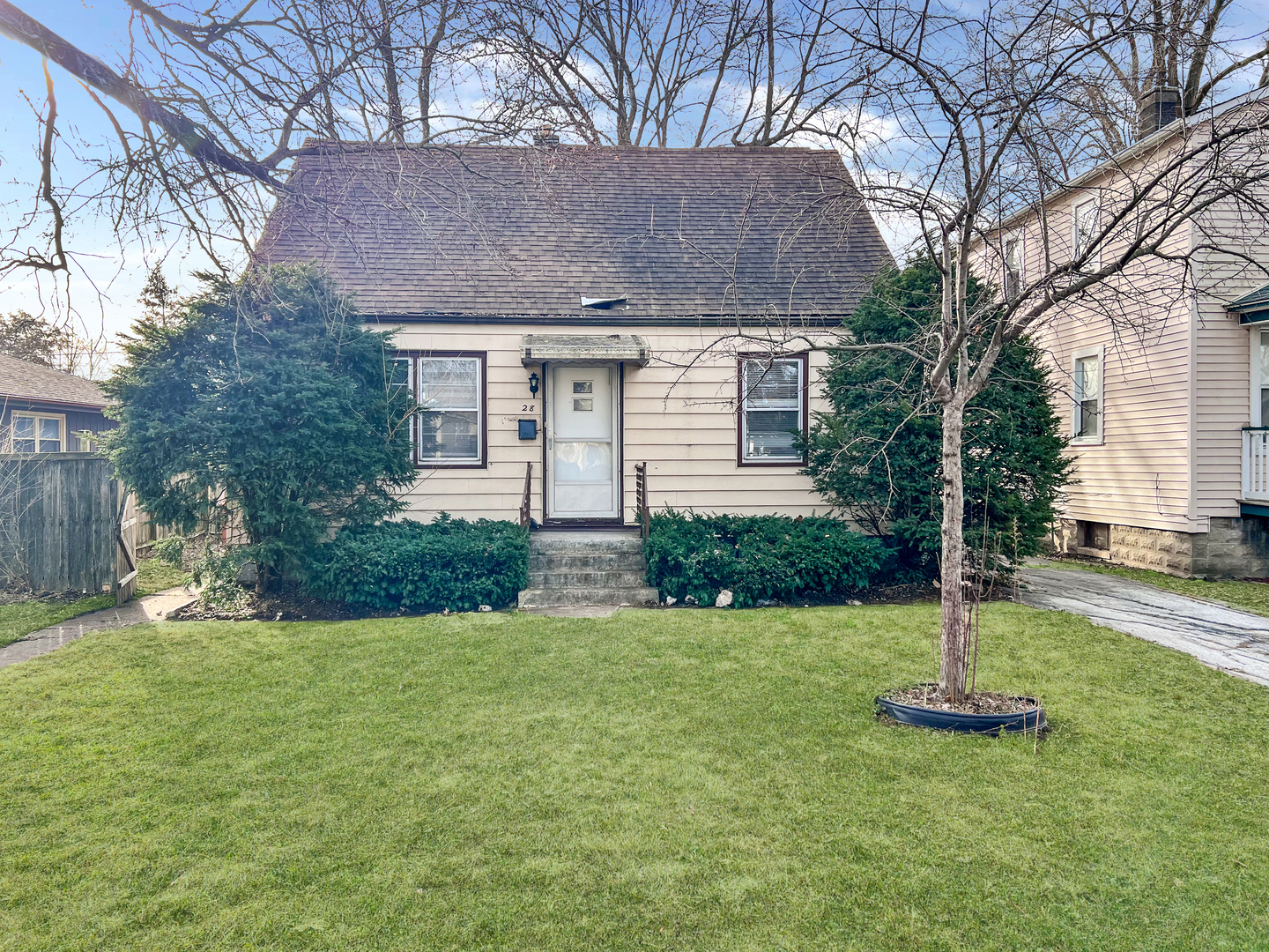 a front view of a house with a yard and a tree
