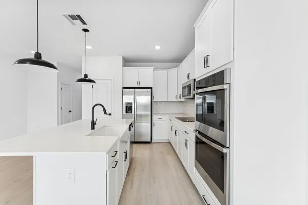 a kitchen with stainless steel appliances a sink a stove a refrigerator and cabinets