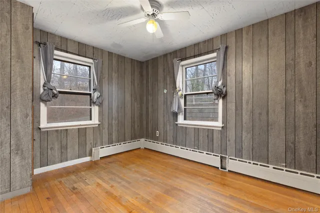 an empty room with wooden floor fan and windows