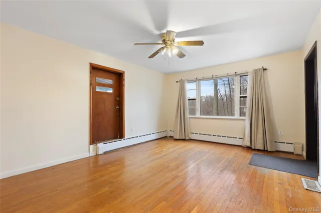 a view of an empty room with wooden floor and a window