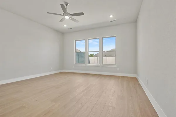 an empty room with windows and chandelier fan