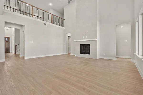 a view of an empty room with wooden floor and a fireplace