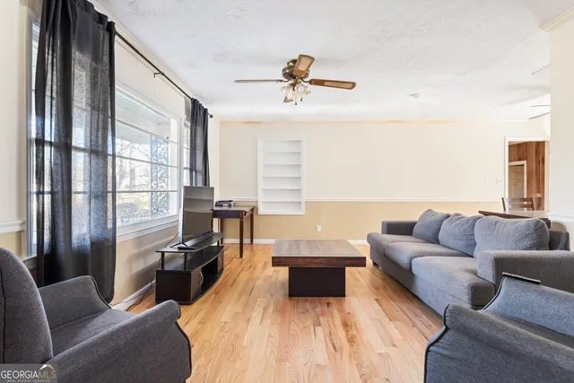 a living room with furniture a ceiling fan and a flat screen tv