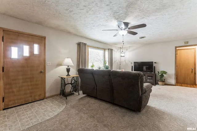 a living room with furniture a chandelier fan and a window