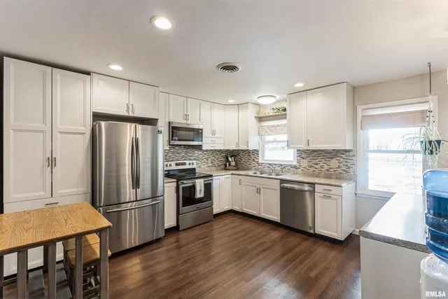 a kitchen with granite countertop a refrigerator stove top oven and sink