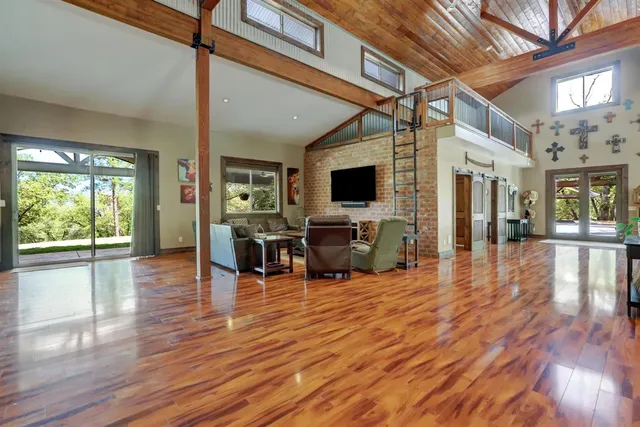 a kitchen with stainless steel appliances granite countertop a stove a refrigerator a sink and a dining table with wooden floor