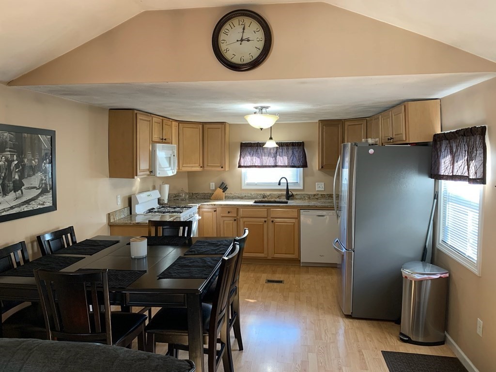 846 Broadway, Unit 45 Saugus, MA 01906 - Photo 4 of 11 a kitchen with a refrigerator a stove top oven a dining table and chairs