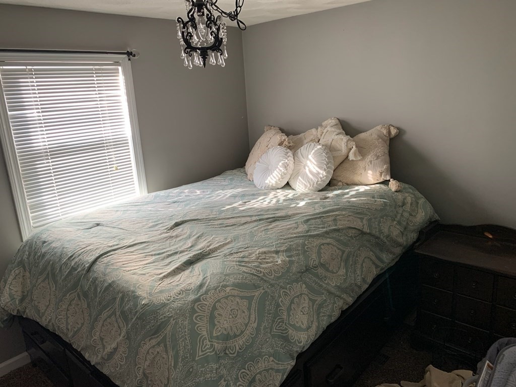 846 Broadway, Unit 45 Saugus, MA 01906 - Photo 8 of 11 a bed sitting in a bedroom next to a window and a chandelier