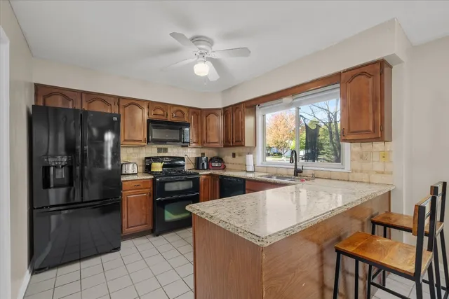 a kitchen with granite countertop a refrigerator oven a sink dishwasher and white cabinets with wooden floor