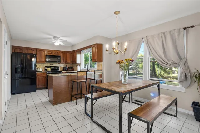 a kitchen with stainless steel appliances granite countertop a refrigerator a oven a sink dishwasher and a dining table with wooden floor