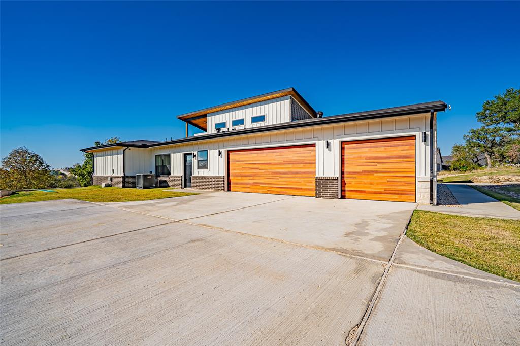 2128 Eagles Rdg Drive Weatherford, TX 76087 - Photo 18 of 39 Contemporary home featuring board and batten siding, concrete driveway, a front yard, and a garage