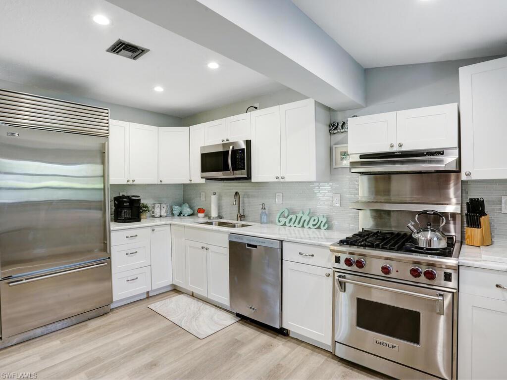1014 Broad Avenue North Naples, FL 34102 - Photo 11 of 33 a kitchen with cabinets stainless steel appliances and wooden floor