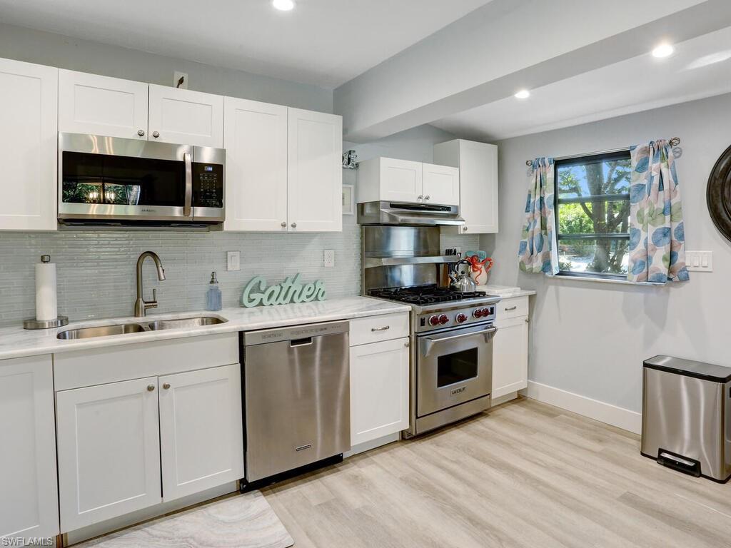 1014 Broad Avenue North Naples, FL 34102 - Photo 12 of 33 a kitchen with cabinets stainless steel appliances and wooden floor