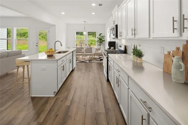 a kitchen with stainless steel appliances a dining table chairs microwave and cabinets