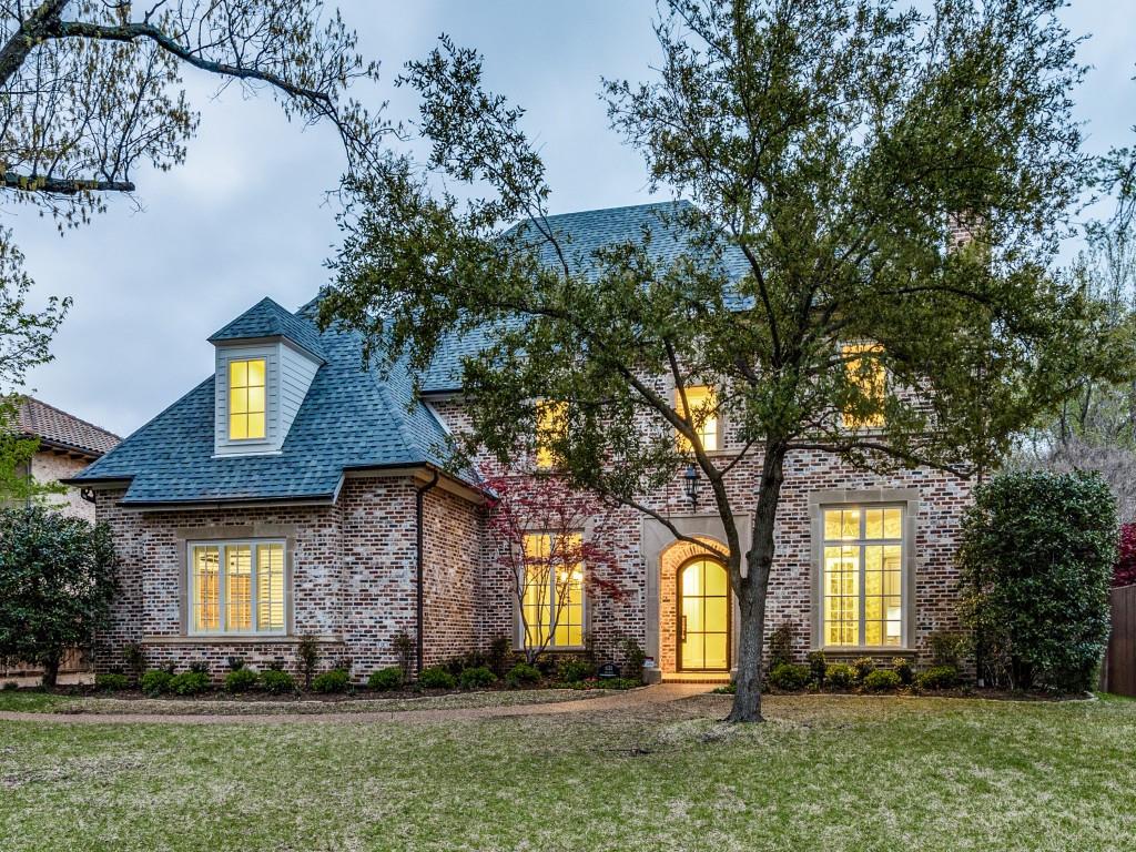 a front view of a house with a yard and a tree