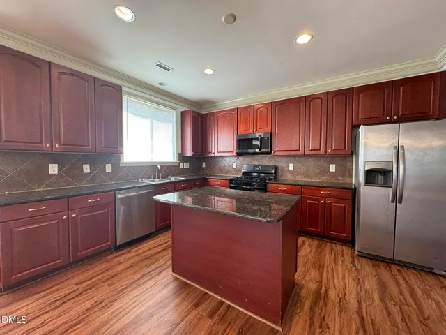 a kitchen with wooden floors wooden cabinets and appliances