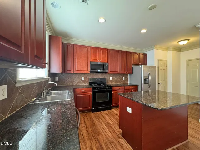 a kitchen with stainless steel appliances granite countertop a stove a sink dishwasher a refrigerator and a microwave oven with wooden cabinets