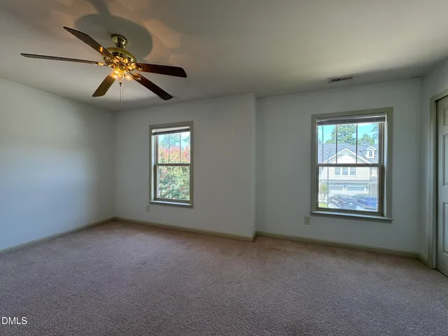 an empty room with windows and fan