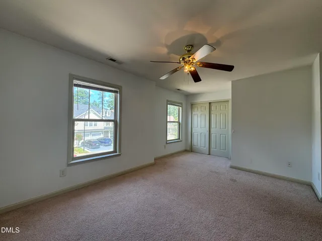 an empty room with fan and windows