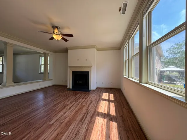 a view of empty room with wooden floor and fan