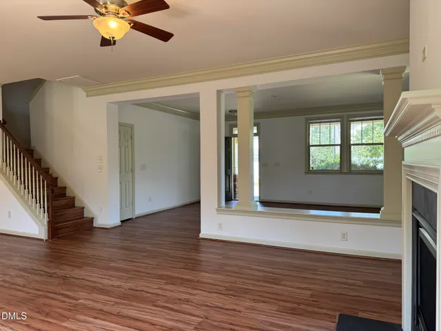 a view of an empty room with wooden floor and a window
