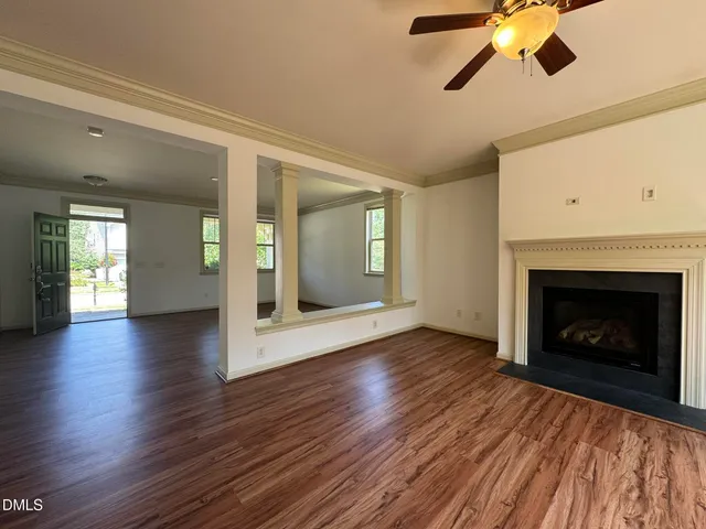 an empty room with wooden floor a fireplace a ceiling fan and a window