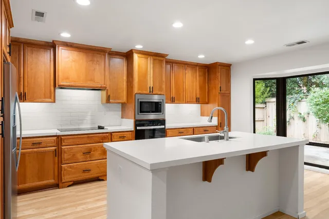a kitchen with stainless steel appliances kitchen island granite countertop a sink stove and cabinets