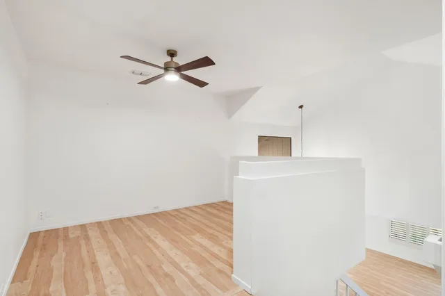 a view of a room with wooden floor and a ceiling fan
