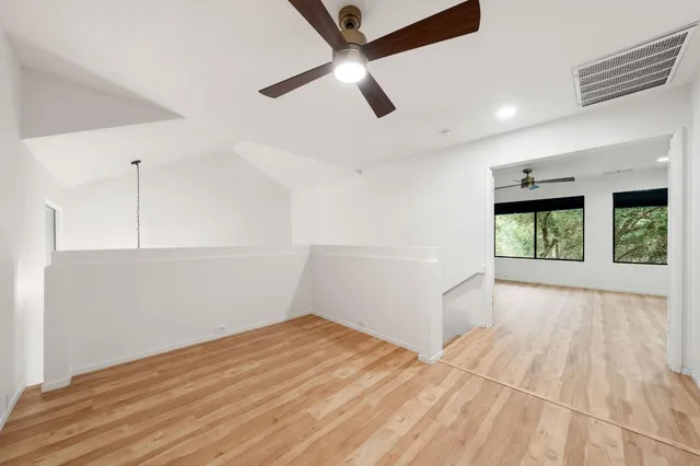 a view of empty room with wooden floor and ceiling fan
