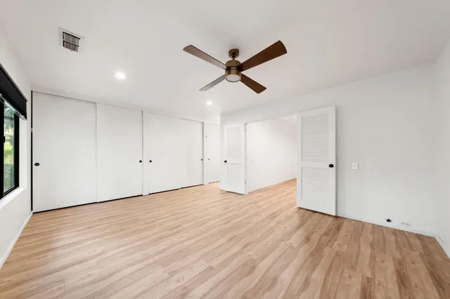 a view of empty room with wooden floor and ceiling fan