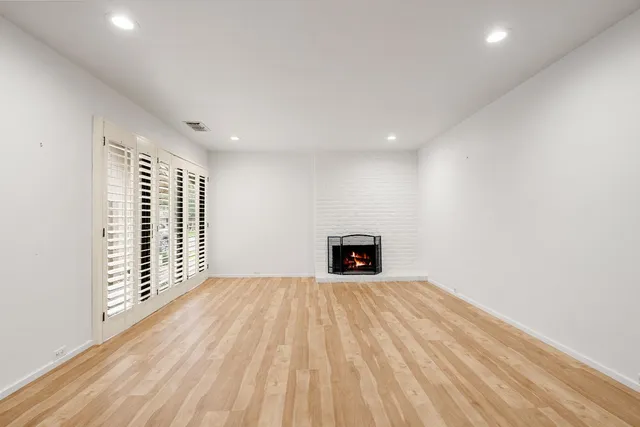 a view of an empty room with a fireplace and a window