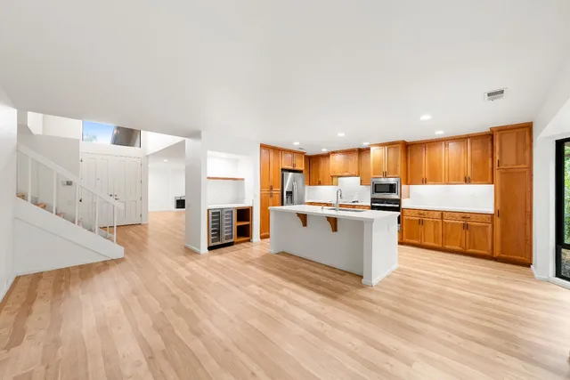 a large kitchen with stainless steel appliances wooden floor a large counter top and a stove