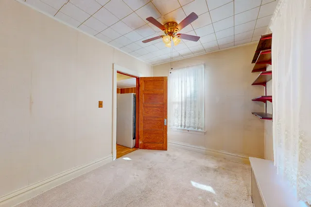 an empty room with a ceiling fan and a window
