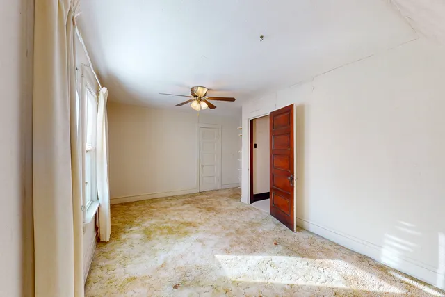 a view of an empty room with a ceiling fan and window