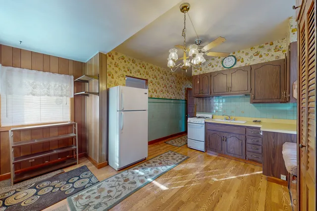 a kitchen with stainless steel appliances granite countertop a refrigerator a sink dishwasher a stove and a dining table with wooden floor