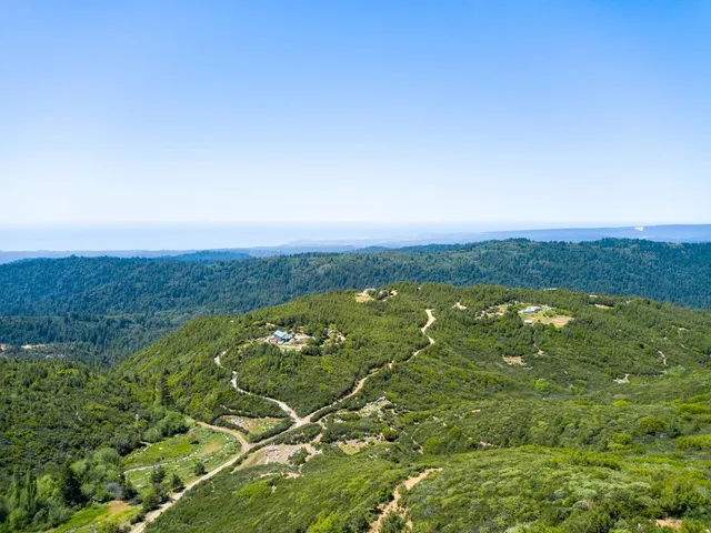 an aerial view of residential houses with outdoor space and trees