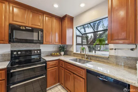 a kitchen with granite countertop wooden cabinets stainless steel appliances and a window